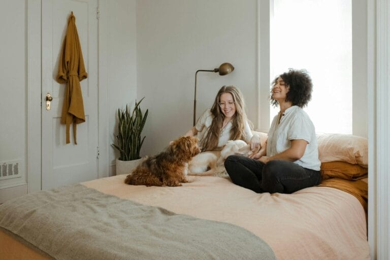 Homepage | curaJOY woman in white long sleeve shirt sitting on bed beside brown dog